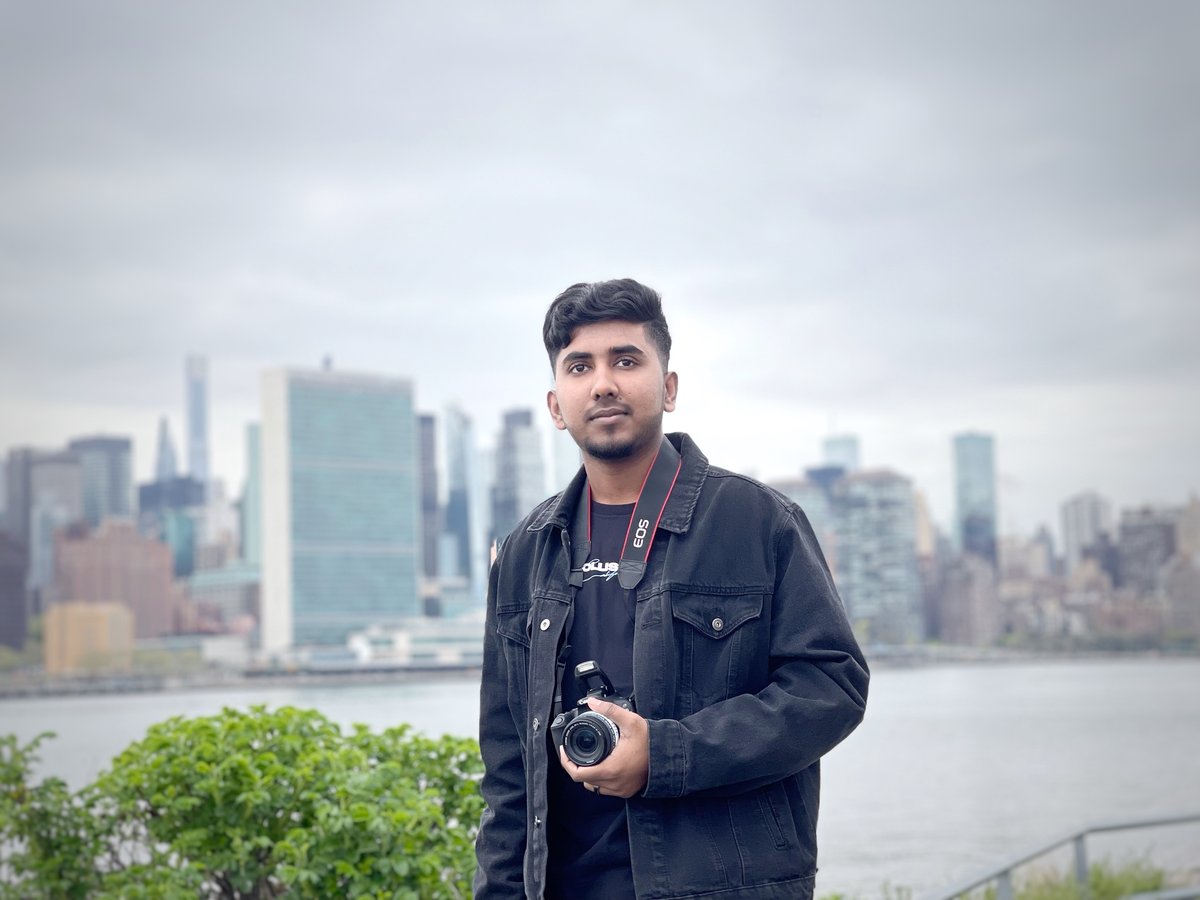 Irfan Rahman holding a camera, Manhattan skyline behind him